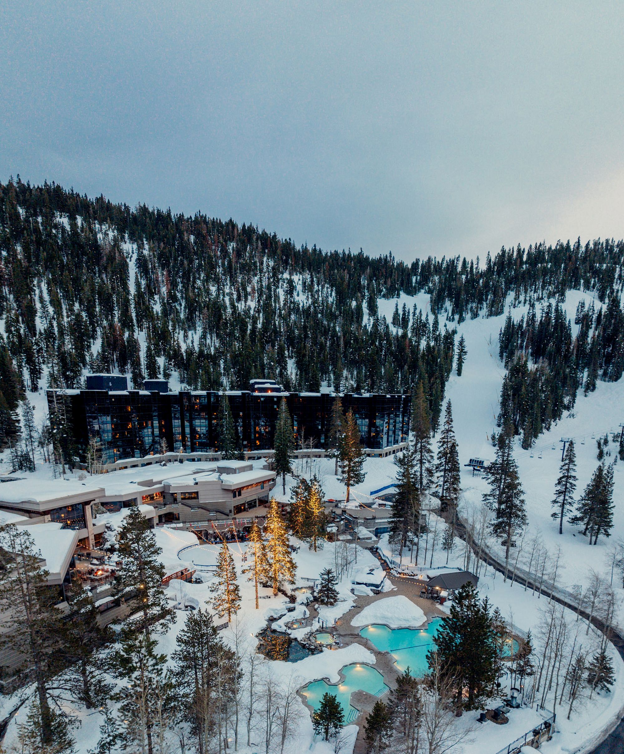 Aerial winter view of Everline Midrise tower, outdoor pools, and ski-in slopes